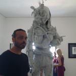 In foto, Lucio Ddtart e la sua scultura "Man", un uomo del futuro che riesce a vivere solo attraverso la sua tuta, con un bambino in braccio, l’ultima speranza di vita in un mondo distrutto dal nucleare, in esposizione nella stanza dedicata alla madre terra (II piano di Castel dell’Ovo) \ilmondodisuk.com